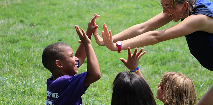 Photograph of woman high-fiving children